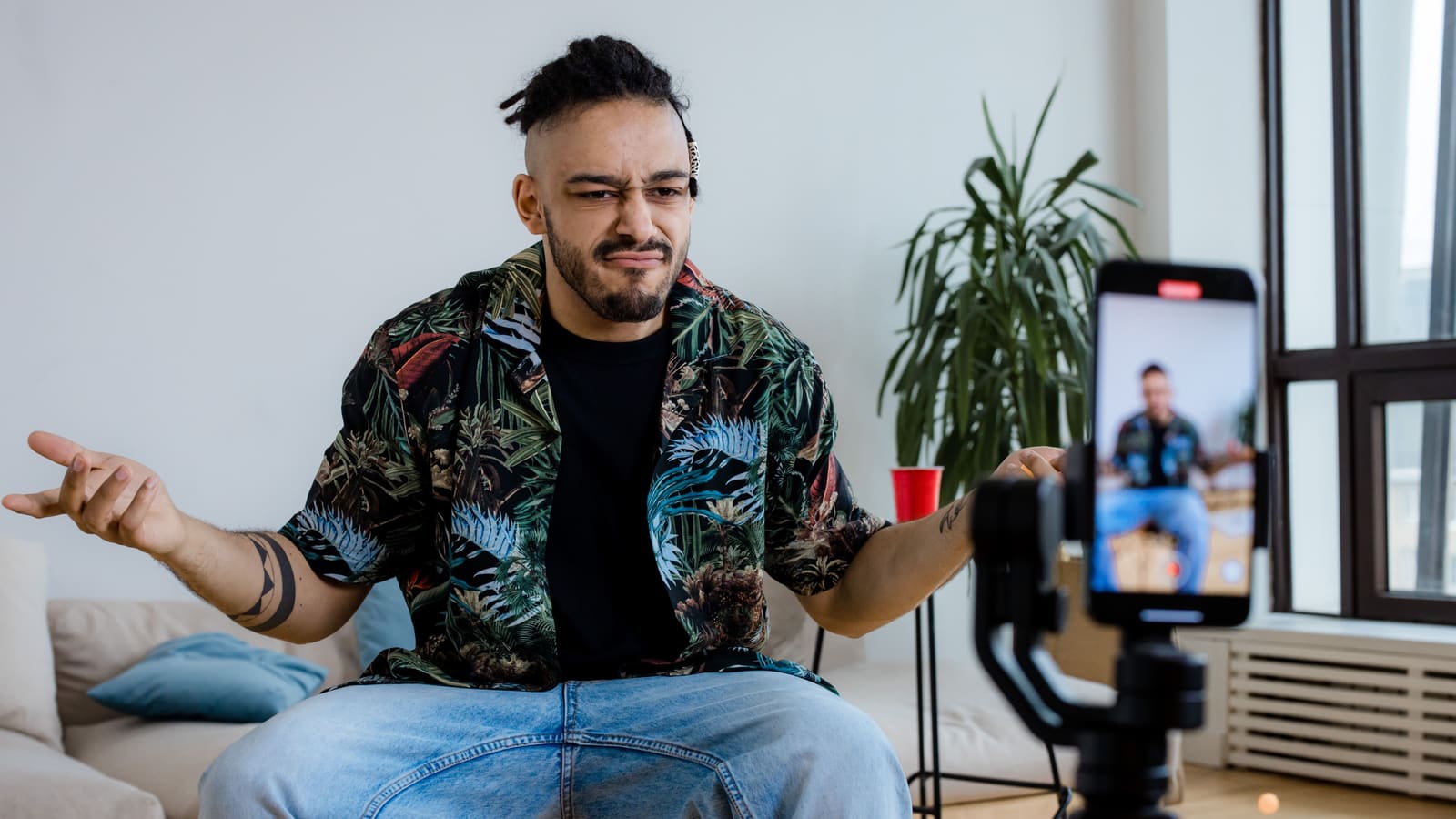 A creator shrugging skeptically at a phone recording him vertically, the doubt behind whether posting Shorts helps or hurts a channel
