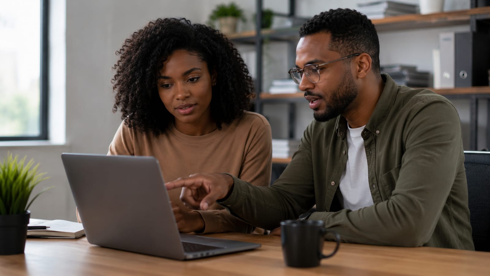 Two people looking at a laptop together, one pointing at a YouTube Studio permissions screen
