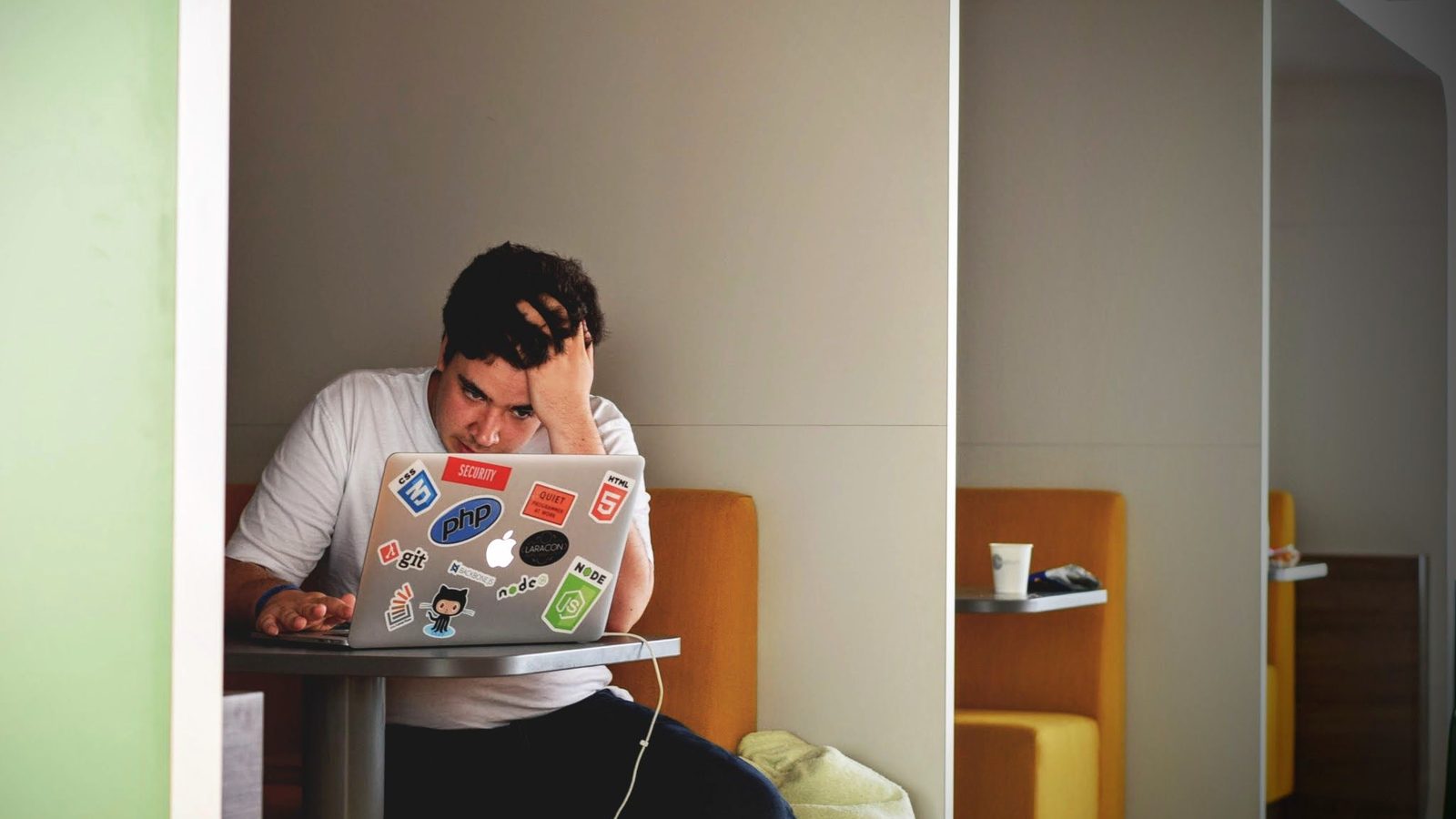 A creator sitting at a laptop covered in stickers, head in hand, the kind of moment a demonetization notice triggers
